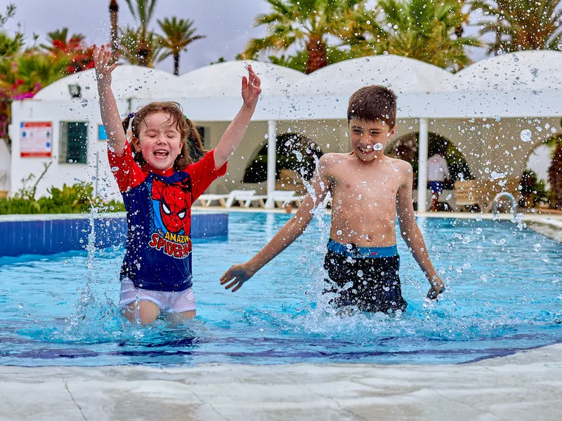 Niños felices saltando en la piscina